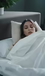 a woman with closed eyes is sleeping in bed