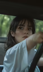 a woman with short hair in a car is holding the steering wheel