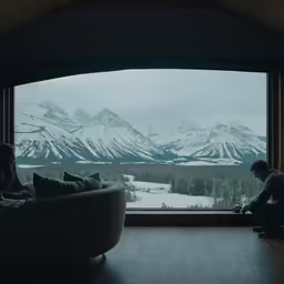 two people look out a window at snow - covered mountains