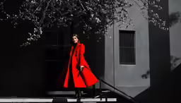a woman walking down the steps while wearing a red coat