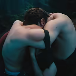 two people wearing no shirts are hugging each other