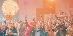 a crowd of people waving and holding up their hands