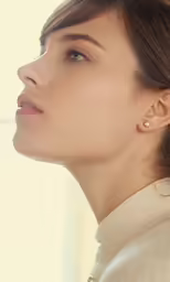 a woman with earring looks up while wearing a jacket