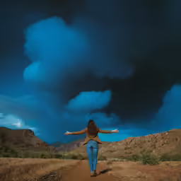 a woman is walking down a dirt road