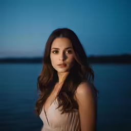 the woman stands by the water looking back at the camera