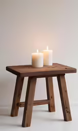 two candles sit on an unfinished wooden table
