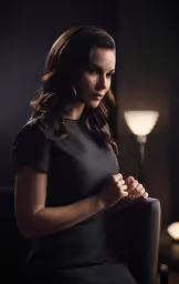 a woman in a black dress standing near a lamp