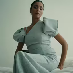the model is sitting on top of a bed