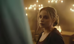 a woman with blonde hair standing in front of a window