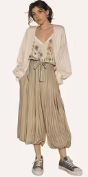 a woman wearing pleated pants with an open neck
