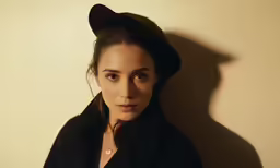 a woman in a black coat and hat posing