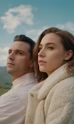 a man and woman are sitting together in a field