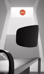 a room with white walls, a black and white chair, and the symbol epic