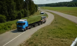 a semi truck is hauling a trailer down the road,two blue semi trucks driving down a road