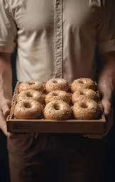a person is holding a box full of bagels