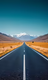 the road is long and empty with mountains in the background