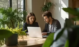 a couple in their home sitting in front of a laptop computer
