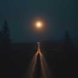 the sun shining on an empty country road at night
