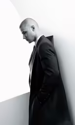 man in black and white photo with bag leaning against wall