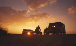a man and a car are silhouetted at sunset