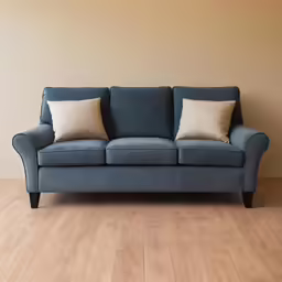 an empty blue couch with two brown pillows