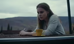 a girl with her hand on a coffee cup sitting outside