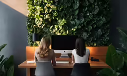 two women are sitting in front of a computer