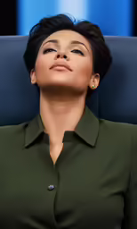 a woman wearing an emerald green blouse sitting in a chair