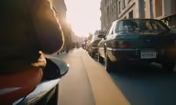 cars are parked along side of each other as a person is holding his phone