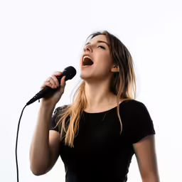young woman singing into microphone with black shirt