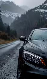 a car driving down a wet road near some mountains