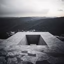 a concrete building with mountains in the background