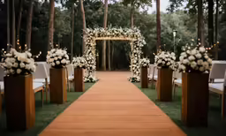 a wooden walkway lined with white flowers and candles