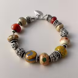 the bead bracelet is made of different colors,a bracelet with some beads and silver items on it