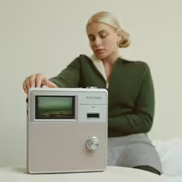 a woman holding a radio on top of a bed