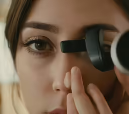 a woman examines a piece of contact lens