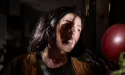 a woman with long hair and a bloody face holding a red balloon