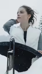 a woman sitting in the snow holding a sled