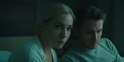 a beautiful young blonde woman sitting next to a man in a bed