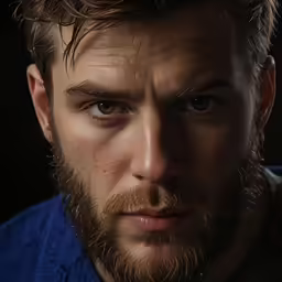 man with wet beard and piercing in dark photo