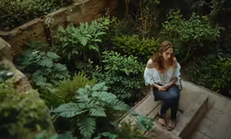 a young lady on the steps is looking down at her cell phone