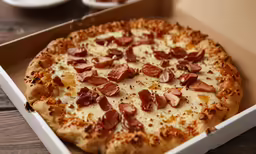 a pizza with ham sits in a box
