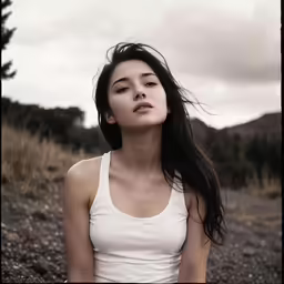 a woman is sitting on the rocks while the wind blows her hair