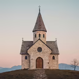 a small church sits atop the grass at sunset