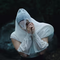 the veiled girl in white is holding her hands together