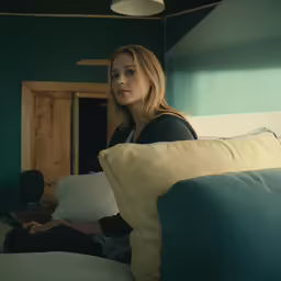 the woman is sitting on her bed looking at something