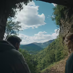 a couple watching the view from the ledge of a cave