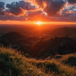 sunset seen over hills with grass on the ground