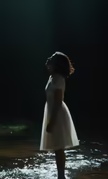 a girl in white dress in water looking into dark