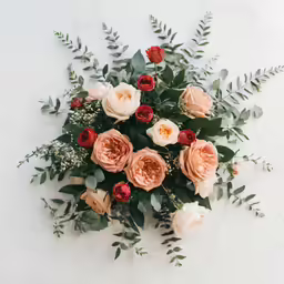 many orange flowers surrounded by greenery on white marble surface